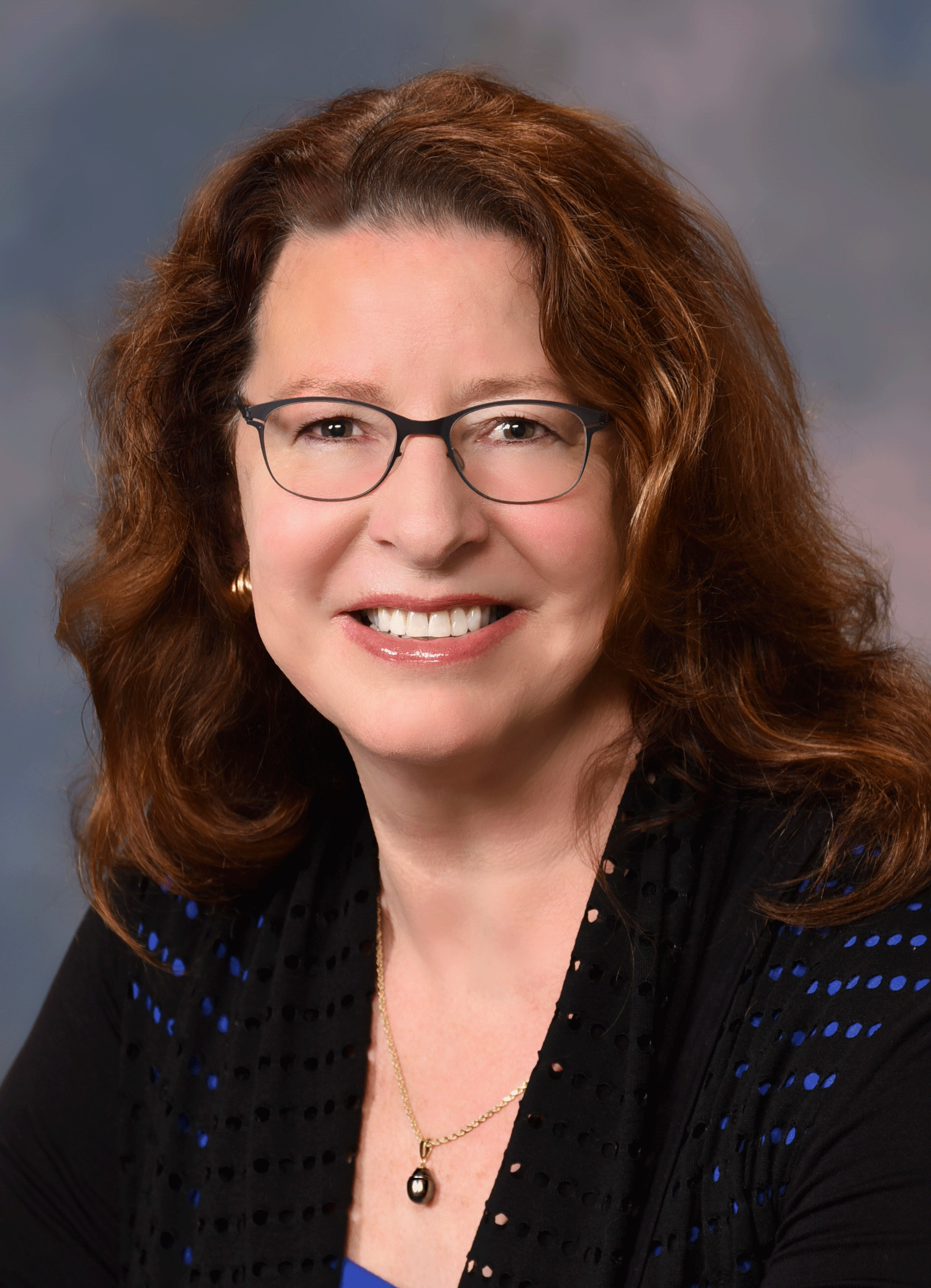 Ann Schneider for Millbrae City Council District 3. Woman with auburn hair and glasses, smiling. Ann Schneider, used with permission.