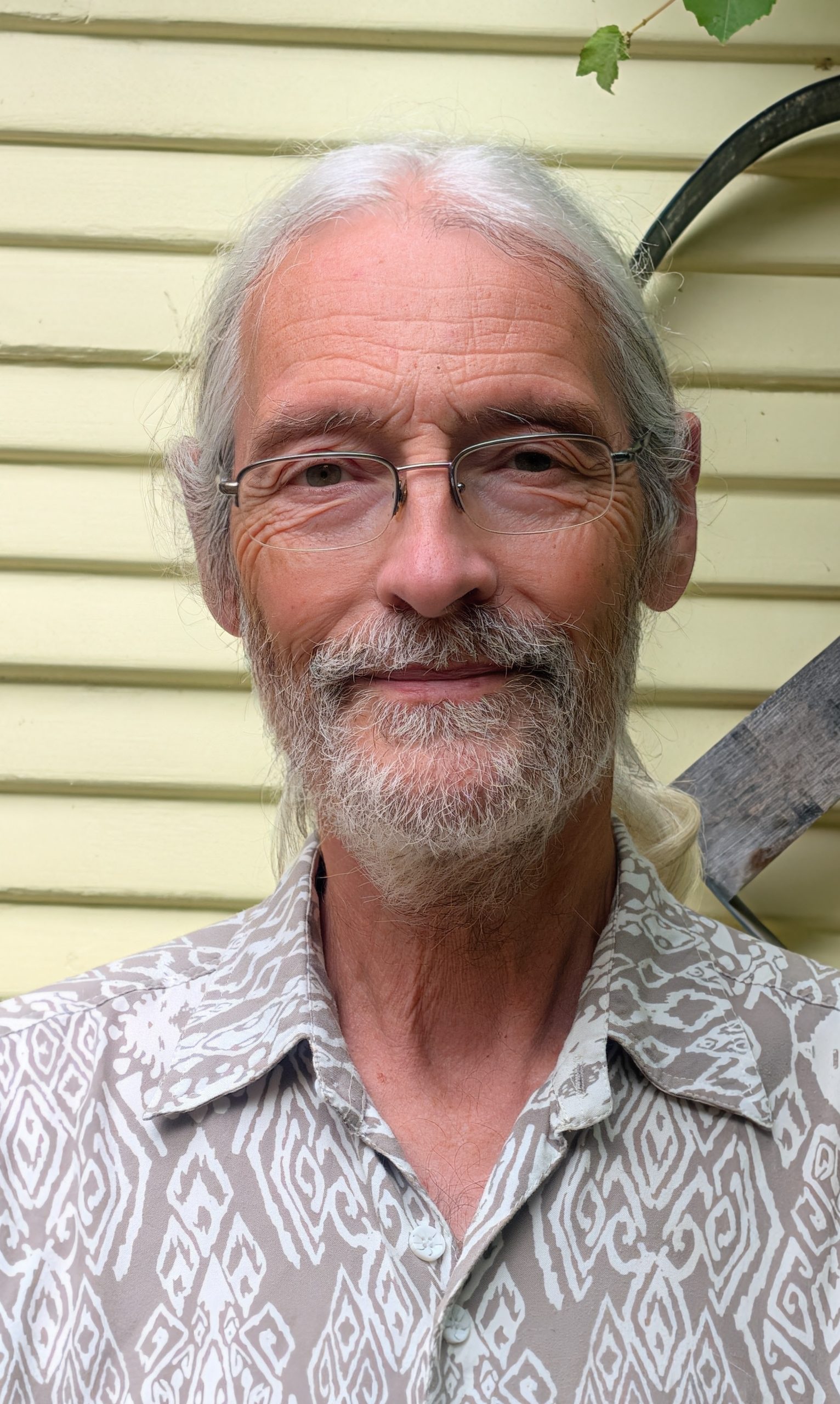 Bruce Ackerman for Fairfax Town Clerk. Man with rimless glasses, looking peaceful in front of a house. Photo credit: Bruce Ackerman, used with permission.